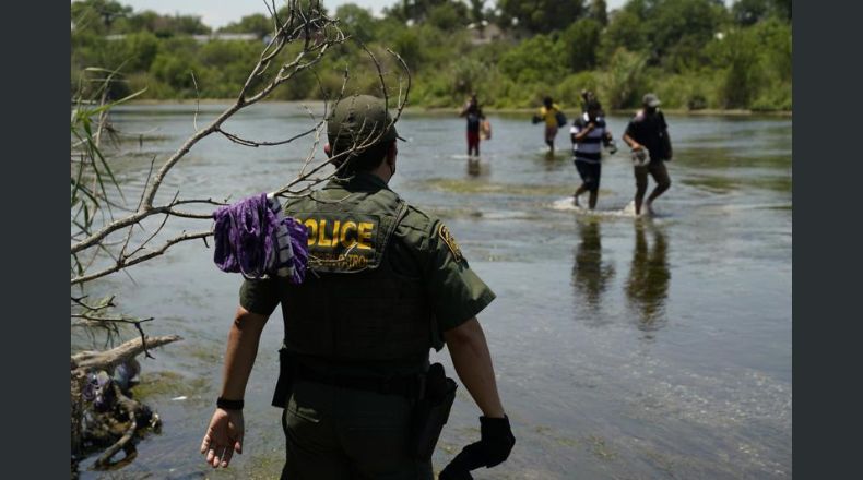 Un agente de la Patrulla Fronteriza de Estados Unidos junto con migrantes que cruzan el río Bravo cerca de Del Rio, Texas, el 15 de junio de 2021. (Foto AP/Eric Gay, archivo)