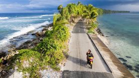 Una pareja en moto pasa por el punto más estrecho de la isla de Fongafale, en el atolón de Funafuti, parte de la nación insular Tuvalu.