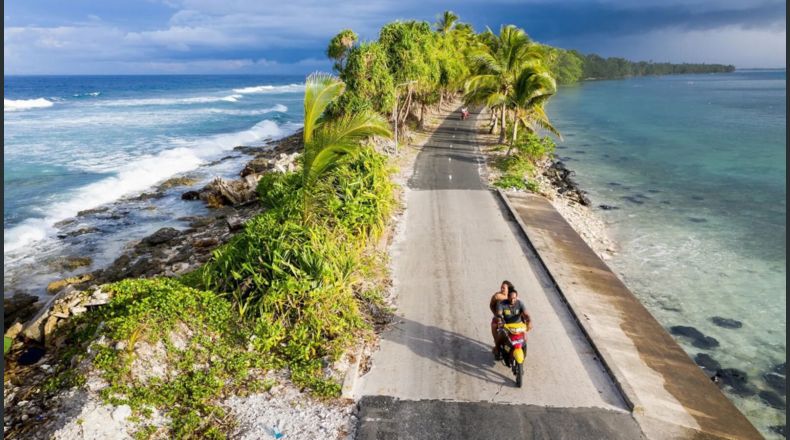 Una pareja en moto pasa por el punto más estrecho de la isla de Fongafale, en el atolón de Funafuti, parte de la nación insular Tuvalu.