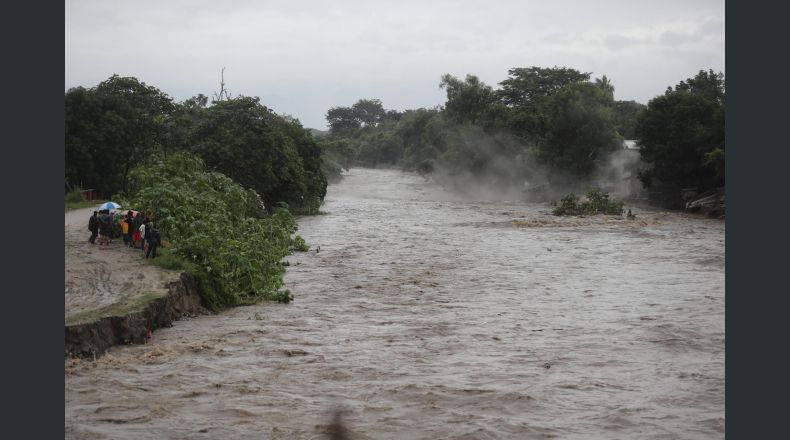 Fotografía que muestra la crecida de un río por el paso de la tormenta Sara, este sábado, en el sector de la aldea Tikamaya, en la ciudad de San Pedro Sula (Honduras). Al menos una persona muerta, más de 40.000 afectadas y 143 comunidades incomunicadas ha dejado la tormenta tropical Sara, que desde el jueves azota con mayor incidencia toda la región caribeña de Honduras, informaron este sábado las autoridades de protección. EFE/ Gustavo Amador